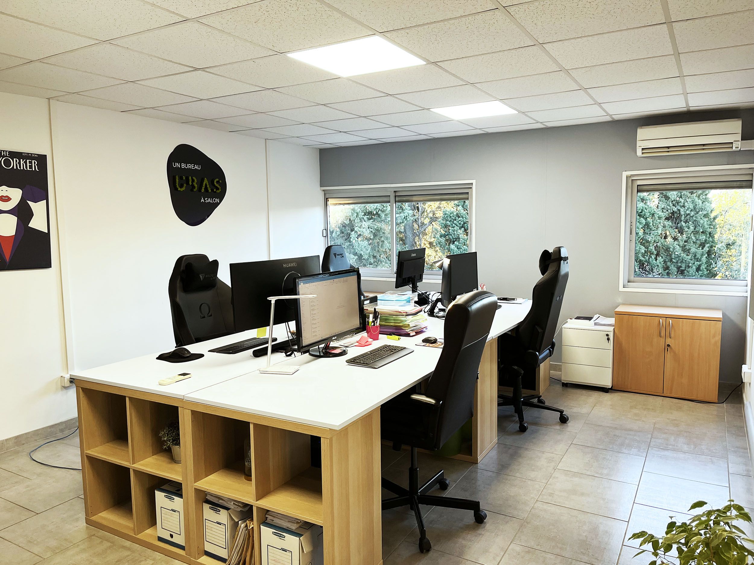 Espace de coworking d’UBAS : grand plan de travail blanc partagé et étagères en bois